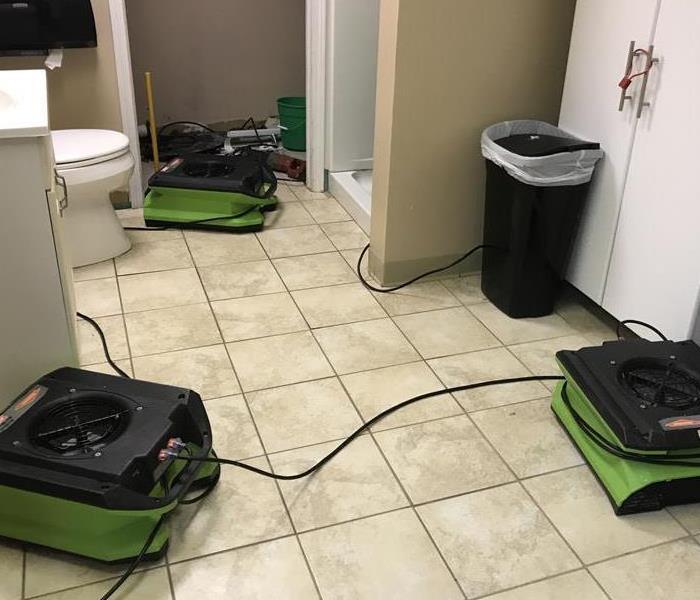 Green air movers and scrubbers on tile floor in bathroom