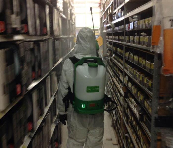 Person in PPE walking through shelves. 