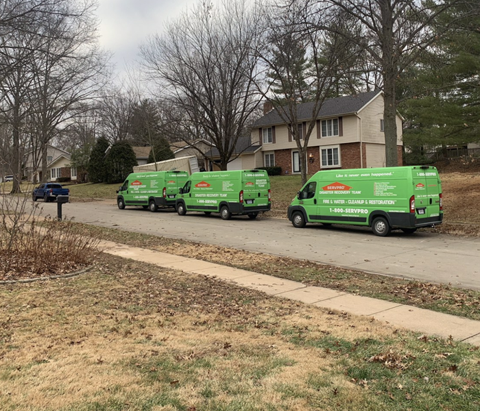 Three green SERVPRO vans parked on the other side of the street. 