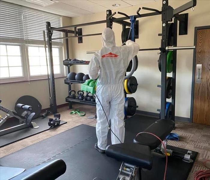 Employee in PPE in a weight room. 